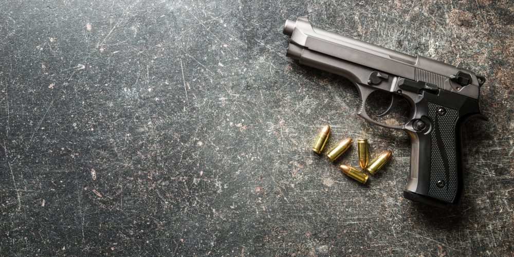 9mm pistol bullets and handgun on black table.